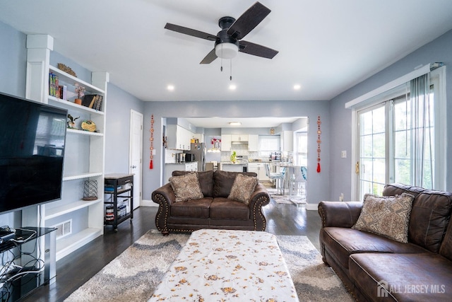 living area with dark wood finished floors, visible vents, a ceiling fan, and baseboards