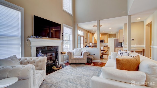 living room featuring light wood-type flooring, a high ceiling, and a high end fireplace