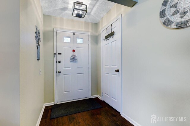 doorway with dark hardwood / wood-style flooring and a textured ceiling