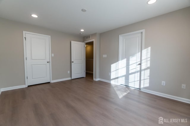 spare room featuring baseboards, recessed lighting, wood finished floors, and visible vents