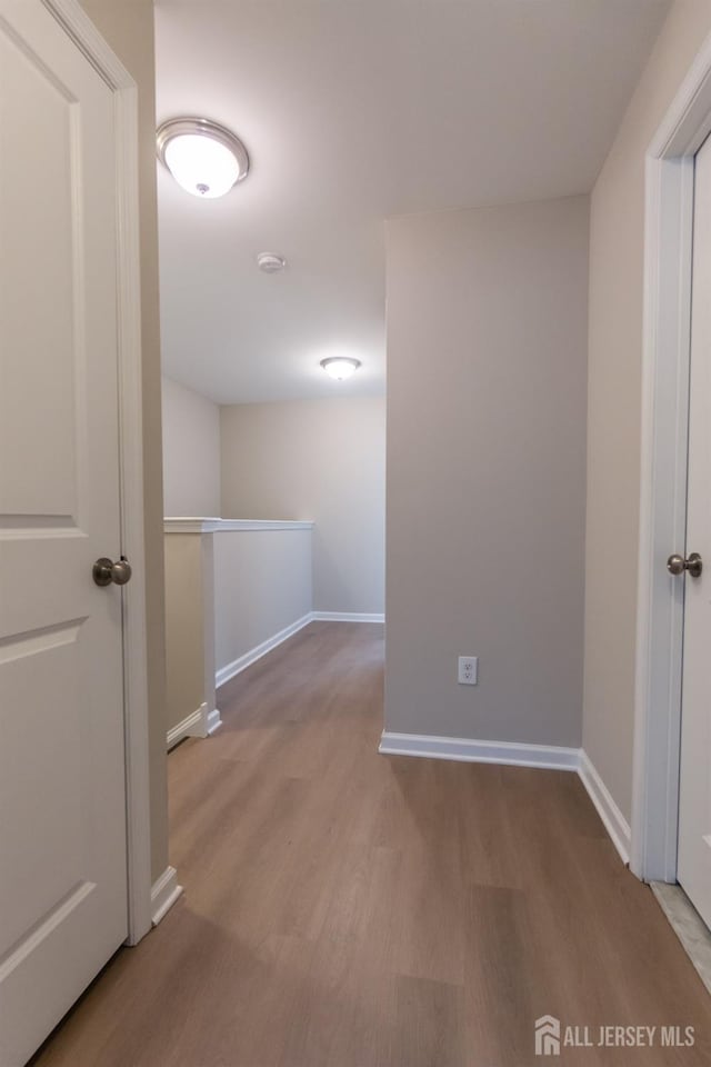 corridor featuring baseboards and wood finished floors