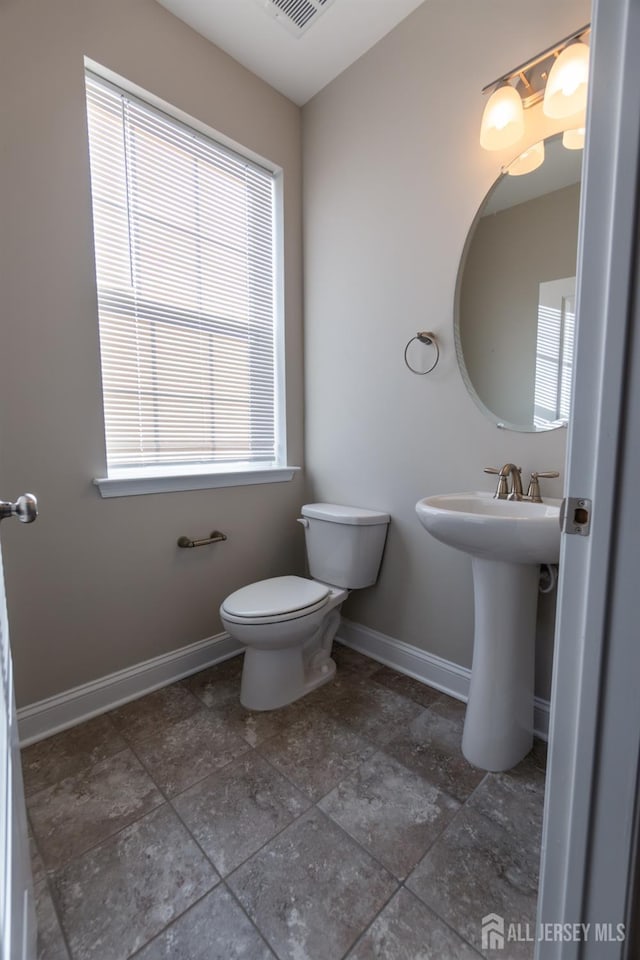 half bathroom with baseboards and toilet