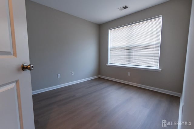 spare room with dark wood-style flooring, baseboards, and visible vents