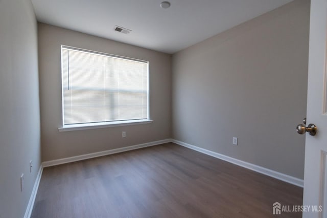 spare room with visible vents, baseboards, and wood finished floors