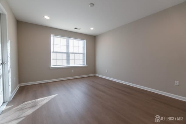 unfurnished room with baseboards, visible vents, and wood finished floors