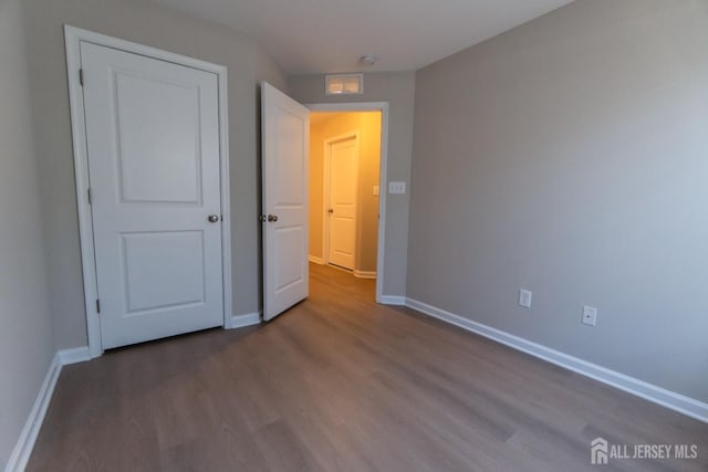 unfurnished bedroom with baseboards and dark wood finished floors