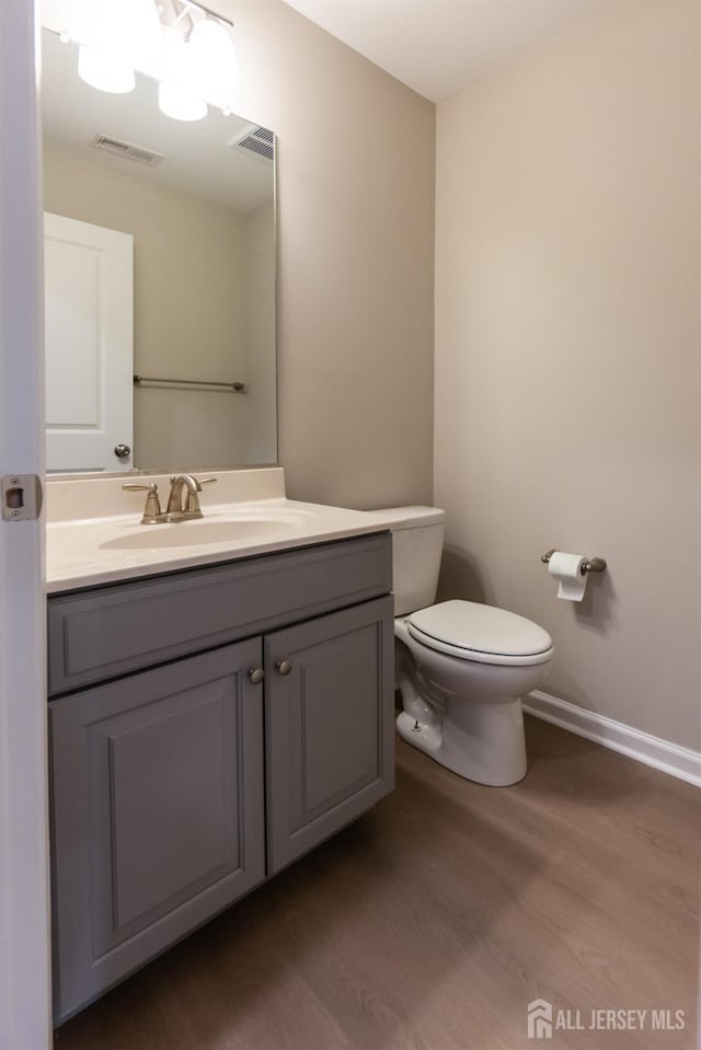 bathroom with visible vents, wood finished floors, toilet, and vanity