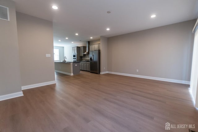 unfurnished living room with recessed lighting, baseboards, visible vents, and wood finished floors