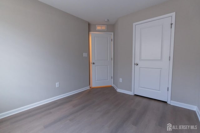 spare room with baseboards and wood finished floors