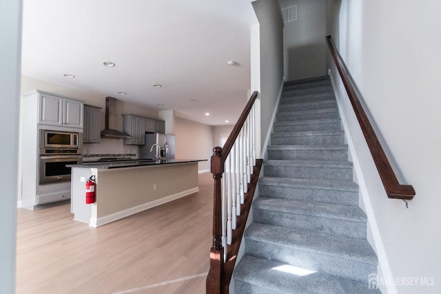 staircase with recessed lighting, baseboards, visible vents, and wood finished floors