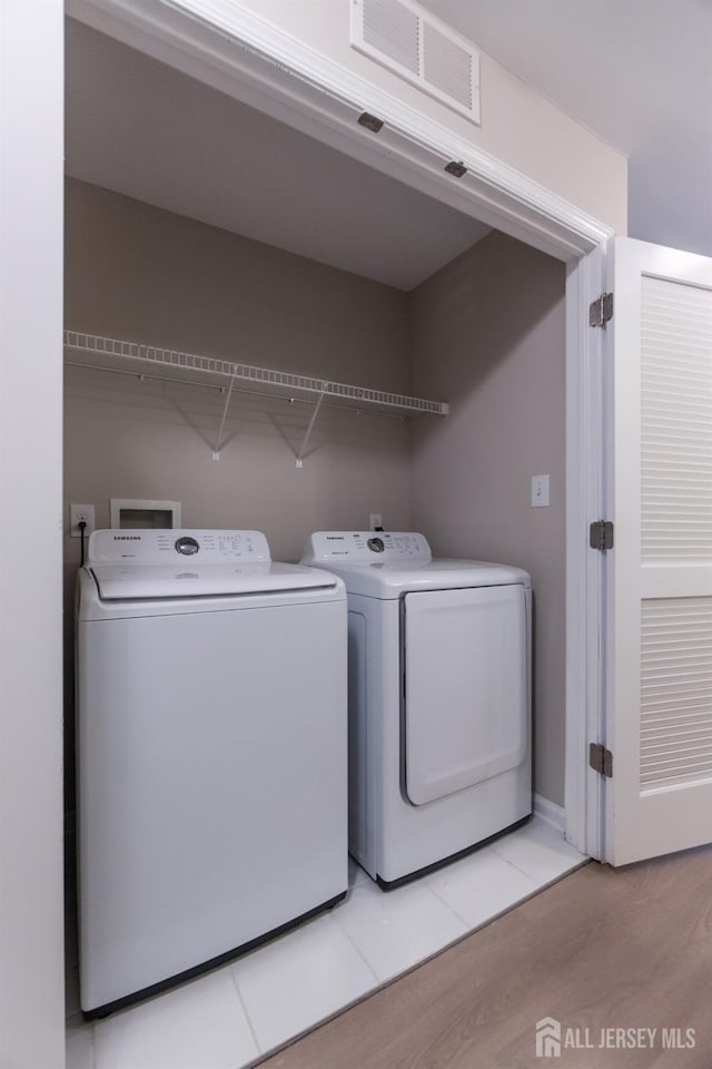 clothes washing area featuring light wood-style floors, laundry area, independent washer and dryer, and visible vents