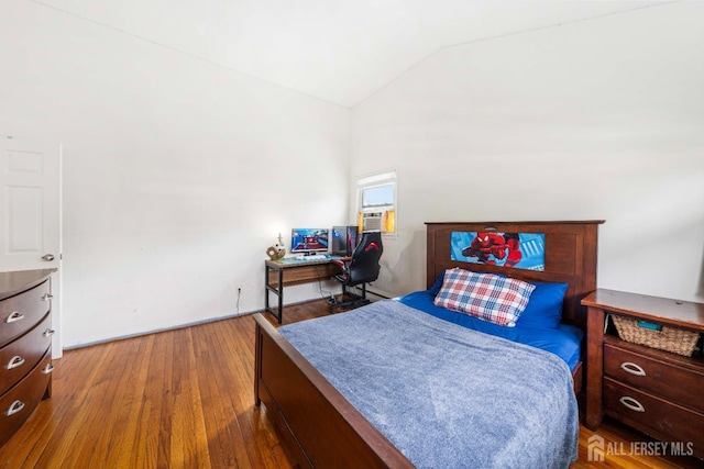 bedroom with cooling unit, vaulted ceiling, and wood-type flooring