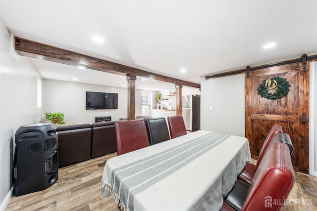 dining space with light wood finished floors, a barn door, beamed ceiling, and recessed lighting