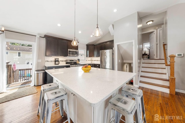 kitchen featuring stainless steel appliances, a center island, dark brown cabinetry, and a kitchen bar