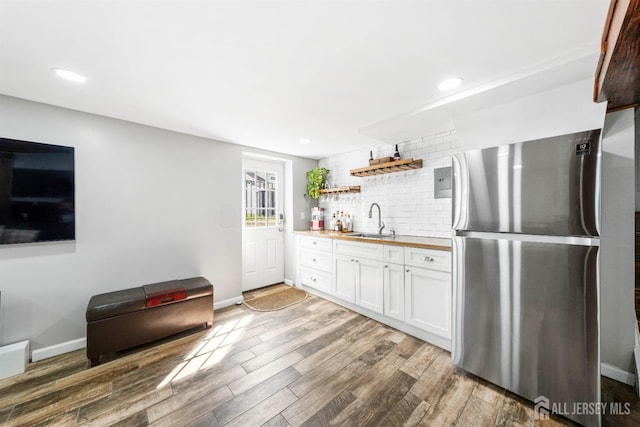 kitchen with tasteful backsplash, sink, white cabinets, stainless steel fridge, and dark hardwood / wood-style flooring