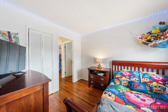 bedroom with dark wood-type flooring and a closet