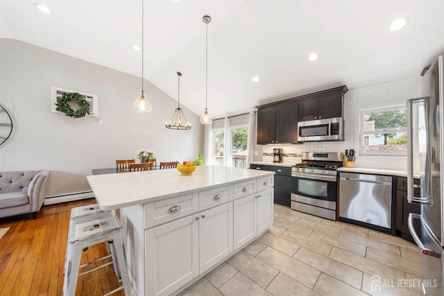 kitchen with a kitchen island, white cabinetry, a kitchen bar, hanging light fixtures, and stainless steel appliances