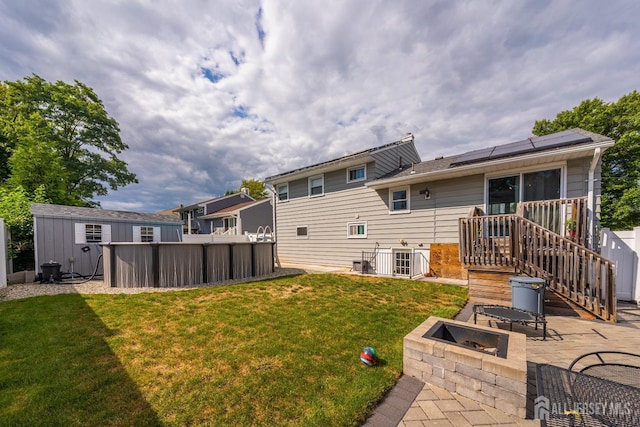 back of property with a lawn, cooling unit, a patio, solar panels, and a storage unit