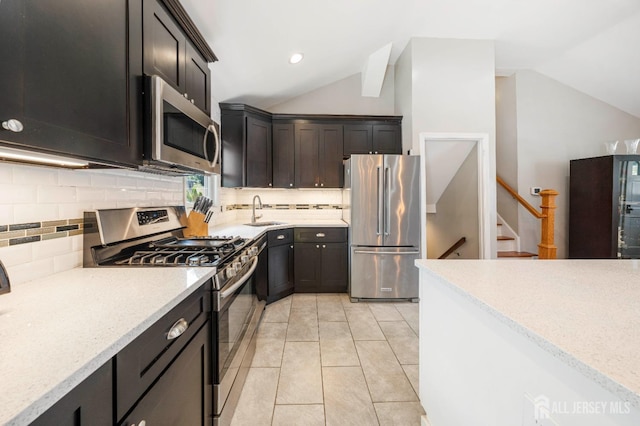 kitchen featuring sink, light tile patterned floors, appliances with stainless steel finishes, backsplash, and vaulted ceiling