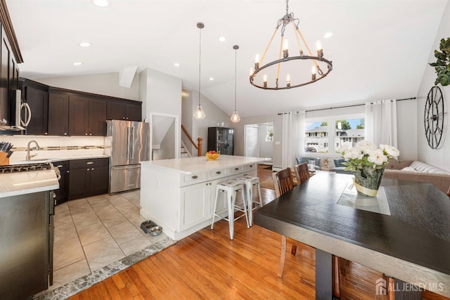 kitchen featuring lofted ceiling, a breakfast bar area, appliances with stainless steel finishes, hanging light fixtures, and a center island