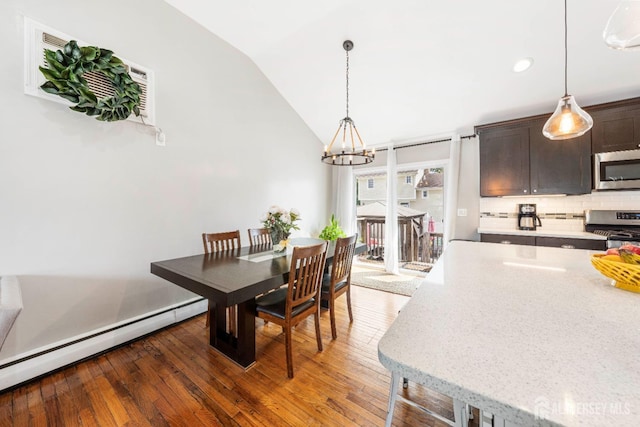 dining space with vaulted ceiling, baseboard heating, dark wood finished floors, and a chandelier