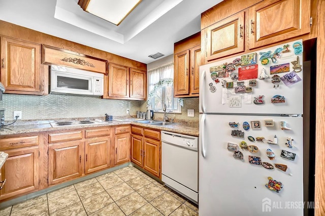 kitchen with light tile patterned flooring, a sink, white appliances, light countertops, and tasteful backsplash