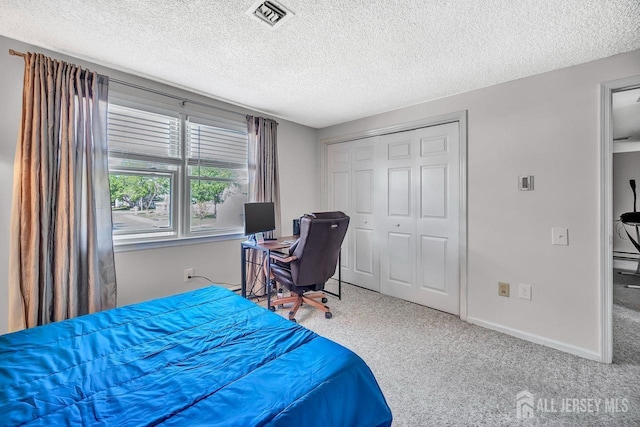 carpeted bedroom featuring visible vents, a textured ceiling, baseboards, and a closet