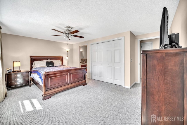 bedroom with a textured ceiling, visible vents, light carpet, and a closet