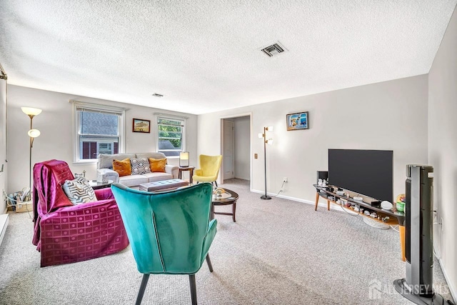 living area featuring visible vents, carpet flooring, a textured ceiling, and baseboards