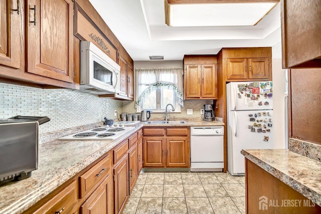kitchen with white appliances, backsplash, a sink, and light countertops