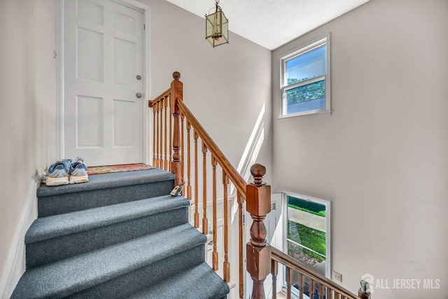 staircase with a high ceiling and a textured ceiling