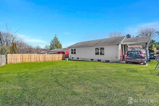 back of property with a yard, a carport, and fence