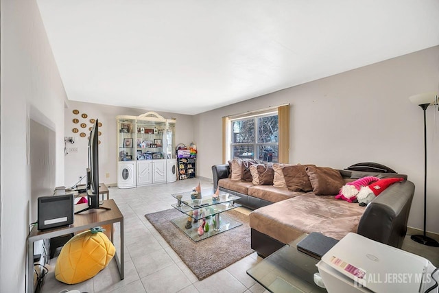 tiled living area with separate washer and dryer and baseboards