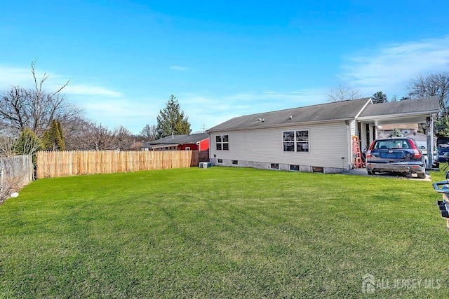 rear view of property with a yard, an attached carport, cooling unit, and fence