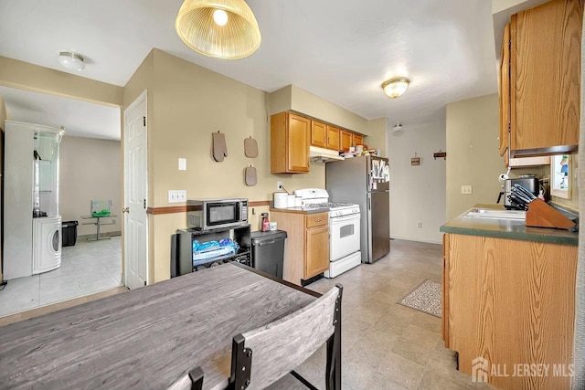 kitchen featuring a sink, stainless steel microwave, washer / clothes dryer, freestanding refrigerator, and white gas range