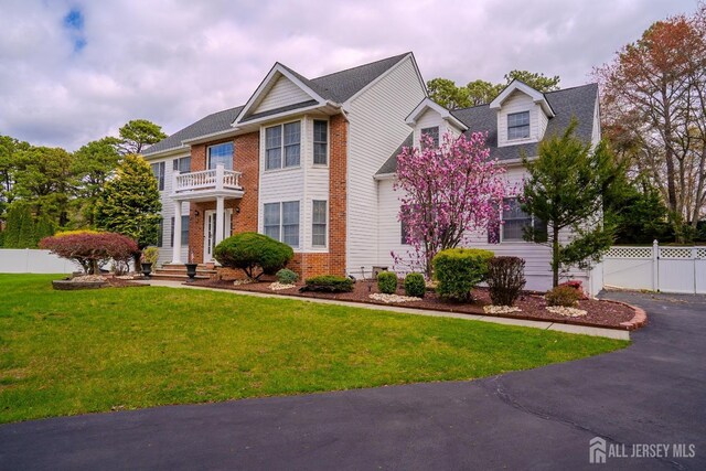 3 Clark Ct, Monroe, NJ 08831 - colonial-style house featuring aphalt driveway, fence, a front lawn, a balcony, and brick siding