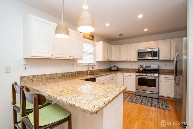 3 Clark Ct, Monroe, NJ 08831 - kitchen featuring a sink, pendant lighting, light wood-style flooring, a peninsula, and appliances with stainless steel finishes