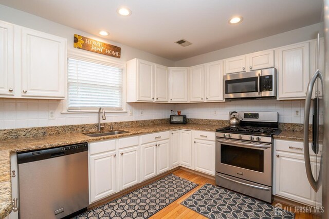 3 Clark Ct, Monroe, NJ 08831 - kitchen with white cabinets, a sink, light wood-type flooring, visible vents, and appliances with stainless steel finishes