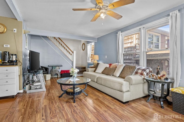 living area featuring stairs, wood finished floors, and a ceiling fan