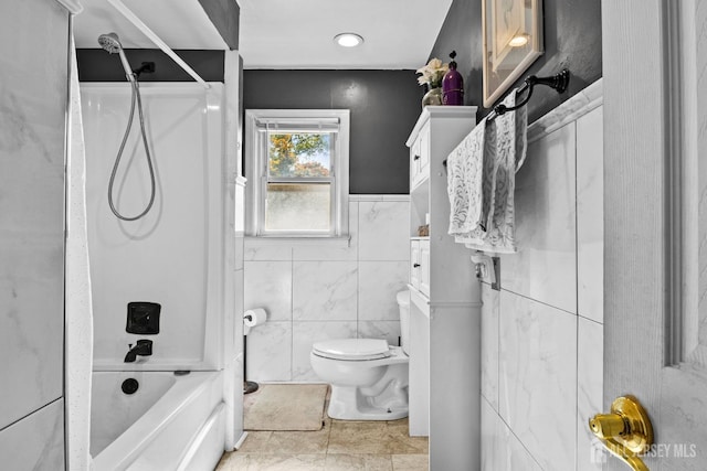 bathroom featuring shower / bath combination, toilet, and tile walls