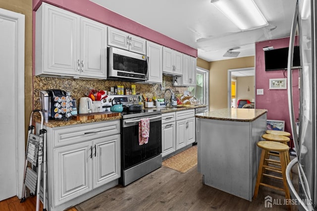 kitchen with dark wood-style floors, stainless steel appliances, white cabinetry, and decorative backsplash