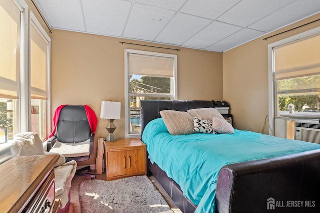 bedroom featuring multiple windows, cooling unit, and a paneled ceiling