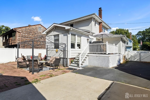 view of front of home featuring a gate, a patio area, fence, and a chimney