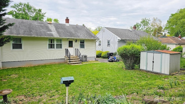 rear view of property with a shed, a chimney, a lawn, cooling unit, and an outdoor structure