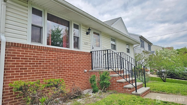 property entrance with brick siding and a yard