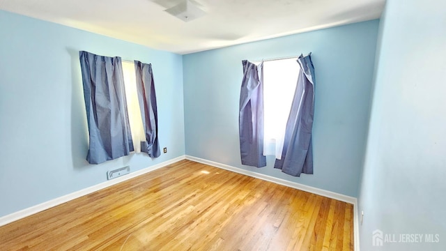 spare room with baseboards and wood finished floors