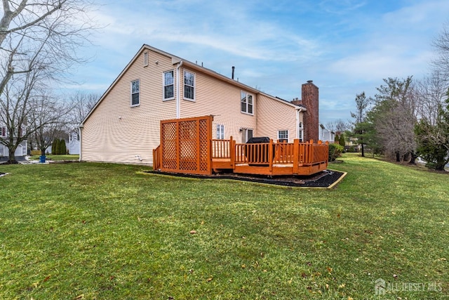 rear view of property with a deck, a lawn, and a chimney