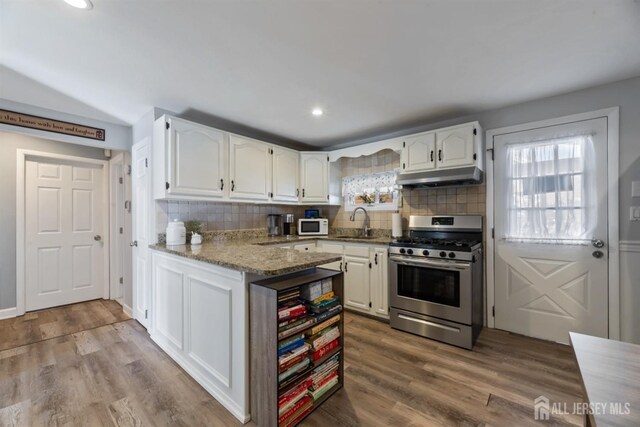 kitchen with sink, hardwood / wood-style flooring, white cabinetry, light stone countertops, and gas stove