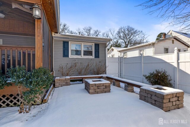 snow covered patio with an outdoor fire pit