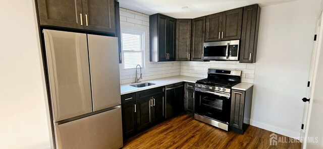 kitchen featuring dark brown cabinetry, appliances with stainless steel finishes, dark hardwood / wood-style flooring, tasteful backsplash, and sink